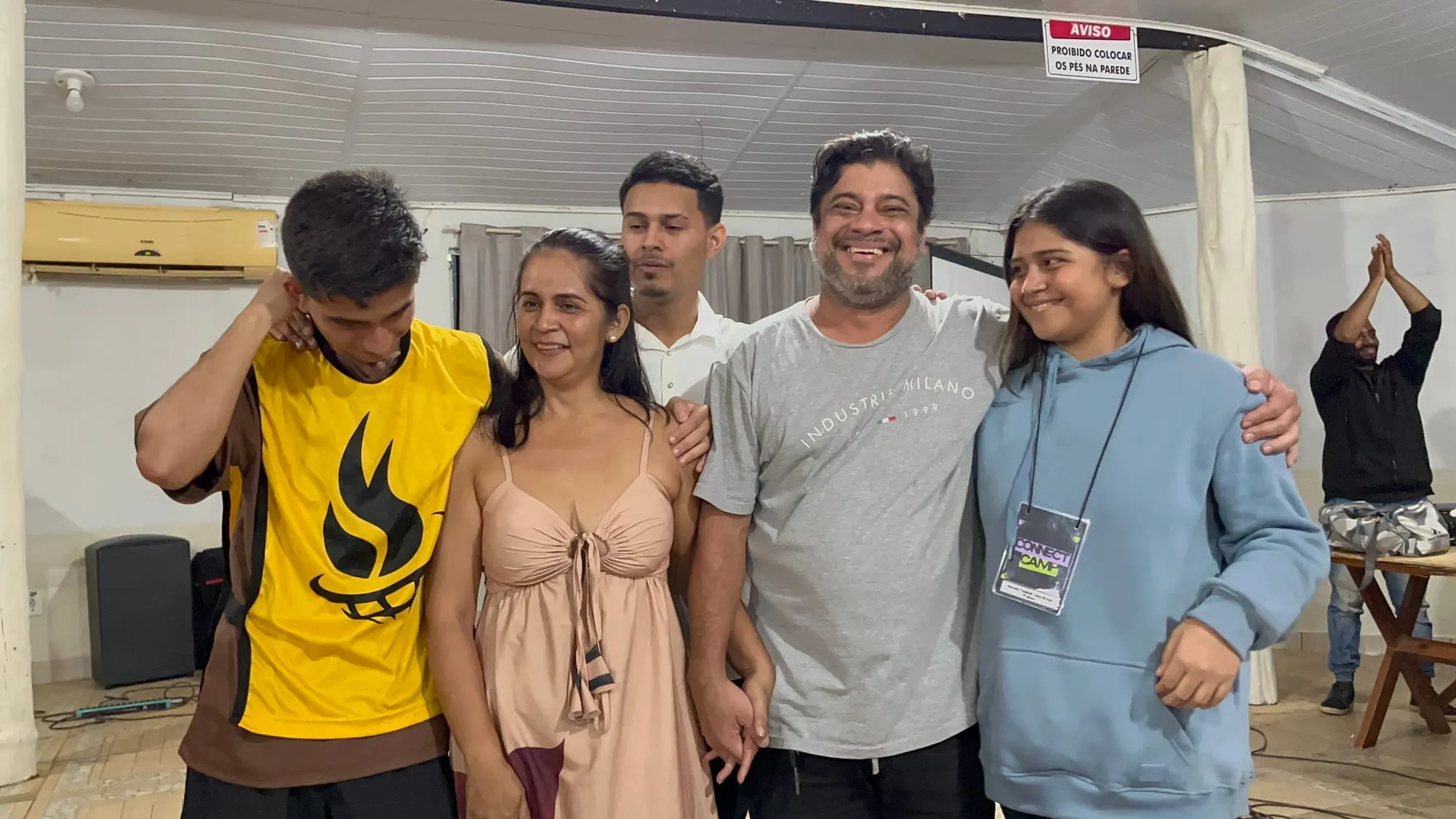 Grupo de amigos abraçados e sorrindo juntos, um deles com a camiseta amarela da Connect