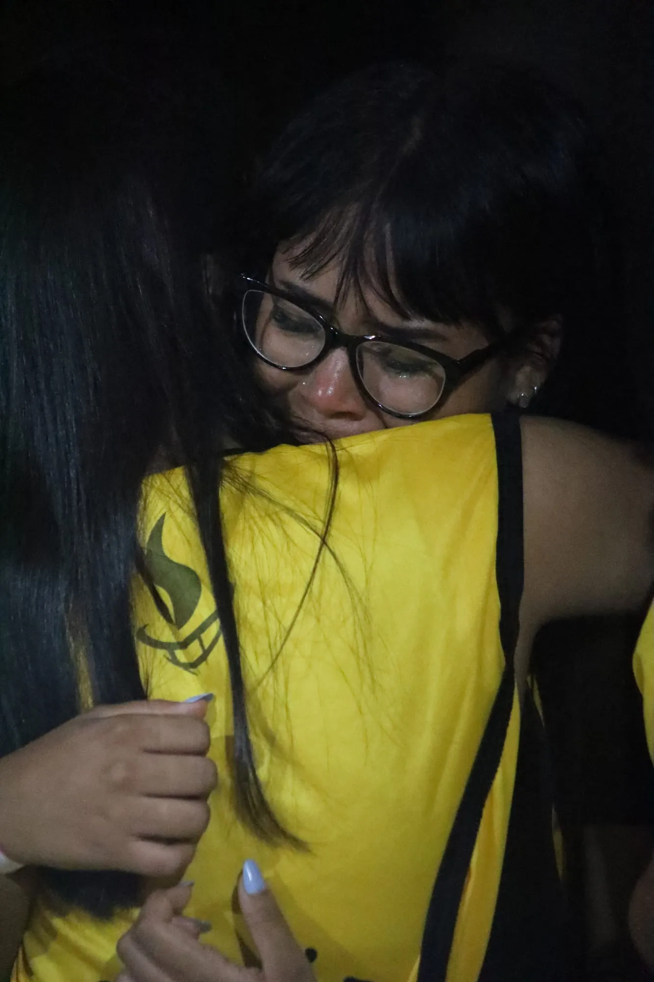 Jovem de óculos emocionada e chorando, amparada em um abraço durante um momento marcante do acampamento